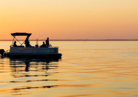 Enjoy a serene sunset fishing scene on the Baltic Sea. A gentle pontoon boat carries fishermen, capturing the beauty of nature and the tranquility of marine recreation.